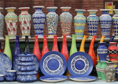Vibrant collection of ceramic vases and plates at an outdoor market showcasing intricate patterns and colors.